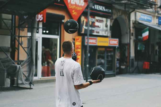 man juggling basketballs near storefront